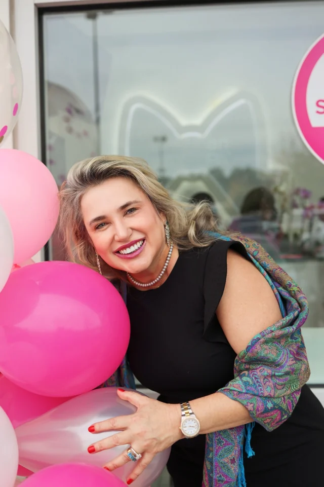 Claudia Rissardi smiling with pink balloons outside her spa